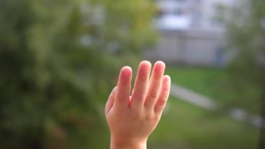 Çocuk pencerede duruyor ve ellerini sallıyor. Elin yakın çekim