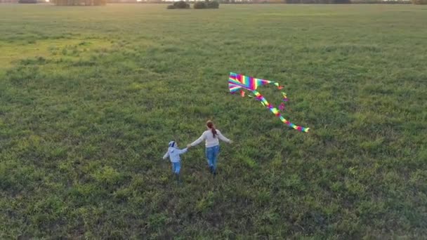 La madre y el niño corren con una cometa en un campo verde. Risa y alegría, humor festivo. Otoño, puesta del sol — Vídeo de stock