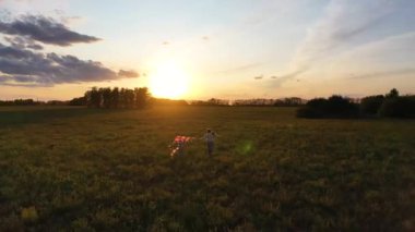 Anne ve çocuk yeşil bir alanda uçurtma ile çalıştırın. Kahkaha ve neşe, şenlikhavası. Sonbahar, Gün Batımı