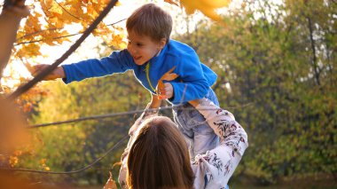 Bir anne çocuğuyla oynar, onu kollarına alır ve kusar. Güneşler çocuğu aydınlatıyor. Ailenin kahkahası ve neşesi.