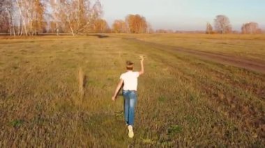 Çocuk elinde bir uçakla sahada koşuyor, uçuş simülasyonu yapıyor. Sonbahar güneşli bir gün. Açık hava eğlencesi