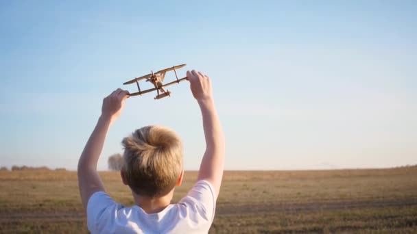 Çocuk elinde bir uçakla sahada koşuyor, uçuş simülasyonu yapıyor. Sonbahar güneşli bir gün. Açık hava eğlencesi — Stok video