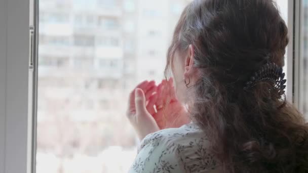 Dziewczyna w masce ochronnej jest w szpitalu. Dziewczyna komunikuje się przez otwarte okno, przesyła pozdrowienia i pocałunki z powietrza. Zapobieganie i ochrona zdrowia i bezpieczeństwa życia. — Wideo stockowe
