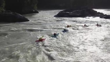 Bir grup insan dağ nehrinde şişme botla yelken açıyor. Rafting sporları
