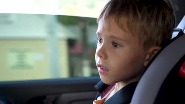 El niño va en un asiento de coche en el coche. Viaje en familia — Vídeo de stock