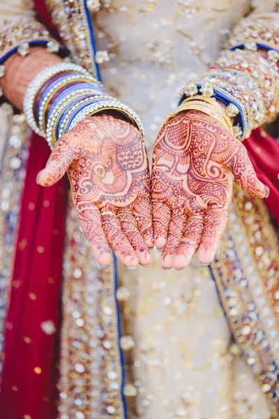 Closeup of Indian bride\'s hands covered with mehndi Holding bangles.