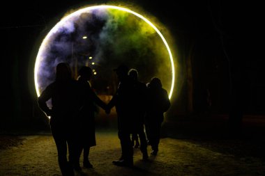 Işık portalı dairesi ve insanları olan soyut ışık huzmesi. Yumuşak seçici odaklanma. Resim için yapay olarak tahıl yaratıldı. Karanlıkta ışık efektleri.