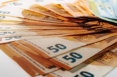 Beyaz bir yüzeye yerleştirilmiş 50 avroluk banknotların yakın plan çekimi, güvenlik özellikleri ve basılı ayrıntılar vurgulandı. 