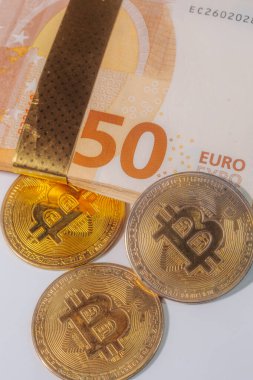 Üç adet Bitcoin jetonu, dijital banknotlar arasındaki farkları sembolize eden 50 avroluk banknotların önüne yerleştirildi.. 