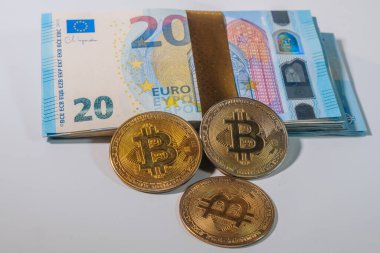 Üç adet Bitcoin jetonu, dijital banknotlar arasındaki farkları sembolize eden 20 avroluk banknotların önüne yerleştirildi.. 