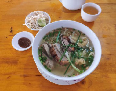 Üzerine kızarmış ördek ve taze taze soğanla süslenmiş domuz etli erişte çorbası..