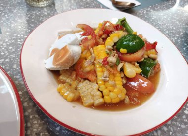 Baharatlı Tayland usulü, tuzlu yumurtalı ve yerel bir restoranda servis edilen mısır salatası..