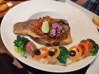 Sos soslu, brokoli, domates ve zeytinle süslenmiş güzel bir kaplanmış deniz kabuğu bifteği..