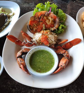 Baharatlı deniz ürünleri sosuyla servis edilen Tayland usulü haşlanmış çamur yengeci..