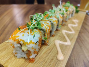 Japon restoranında servis edilen karides yumurtası ve taze ayçiçeği lahanasıyla süslenmiş bir suşi parçası..