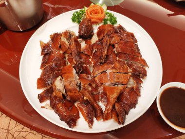 Chinese-style roasted duck with crispy skin, tender meat, and rich savory sauce served banquet style.