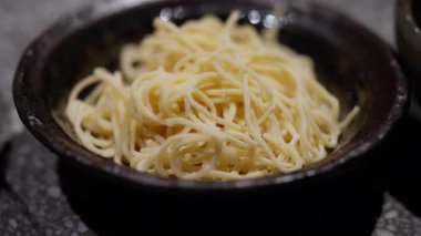 Pürüzsüz, siyah bir kasenin içine zarif bir şekilde yerleştirilmiş taze yumurtalı eriştenin yakın çekimi, canlı sarı renkleri ve pürüzsüz dokuları vurgulanıyor. Mutfak içeriği, restoran promosyonları ya da yemek teması için mükemmel..