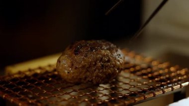 Lezzetli bir Japon hamburg bifteğinin yakın plan çekimi yemek çubukları tarafından nazikçe alınarak yumuşak dokusu ve içerisi lezzetlidir. Mükemmel yemek videoları, yemek blogları. Yüksek kalite 4k görüntü