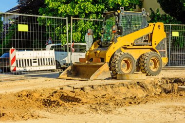 Şehirde bir inşaat alanı, turuncu tarak. Bölgedeki kanalizasyon inşaatı. Park edilmiş iş makinaları yolda. Buldozer Çekme Makinası. Bırakılan yol.