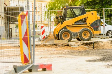 Şehirde bir inşaat alanı, turuncu tarak. Bölgedeki kanalizasyon inşaatı. Park edilmiş iş makinaları yolda. Buldozer Çekme Makinası. Bırakılan yol.