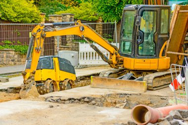 Şehirde bir inşaat alanı, turuncu tarak. Bölgedeki kanalizasyon inşaatı. Park edilmiş iş makinaları yolda. Buldozer Çekme Makinası. Bırakılan yol.