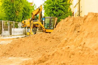 Şehirde bir inşaat alanı, turuncu tarak. Bölgedeki kanalizasyon inşaatı. Park edilmiş iş makinaları yolda. Buldozer Çekme Makinası. Bırakılan yol.