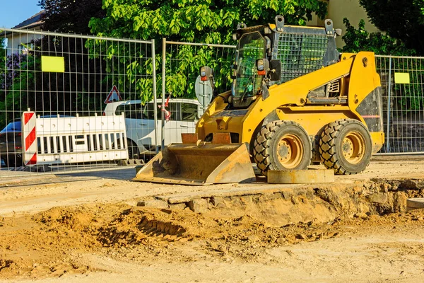 Şehirde bir inşaat alanı, turuncu tarak. Bölgedeki kanalizasyon inşaatı. Park edilmiş iş makinaları yolda. Buldozer Çekme Makinası. Bırakılan yol.