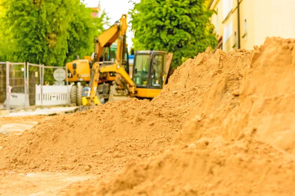 Şehirde bir inşaat alanı, turuncu tarak. Bölgedeki kanalizasyon inşaatı. Park edilmiş iş makinaları yolda. Buldozer Çekme Makinası. Bırakılan yol.