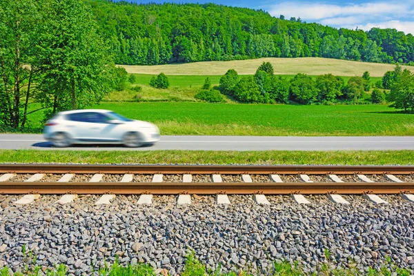 Yol boyunca hızlı hareket eden bir arabanın demiryolu parça gider. Yolun yanındaki çalıştıran parça. Kırsal geçen bir araba güneşli bir görünümünü