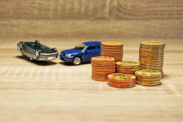 Car model and coin on a wooden table as a concept of buying or renting a car. Loan for buying a car. Czech money at the table. Financial concept with money. Golden coins. Insurance of a car in an accident.
