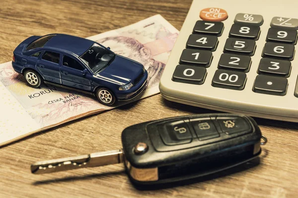 Car keys, banknotes, car model, and calculator as the concept of buying or renting a car. Loan for buying a car. Czech money at the table. Financial concept with money.