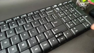 Footage of a finger pressing the Enter key on a modern black mechanical keyboard with a unique key design.