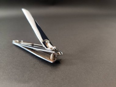 Koyu gri bir yüzeye yerleştirilmiş tırnak makası ya da metal tırnak kesme aracı.
