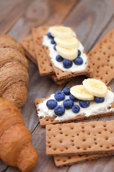 Muz ve ahşap tahta üzerinde ricotta peynirli gevrek aperatifler düz yatıyordu kompozisyon.