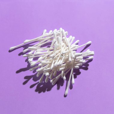 Yığın pamuk kulak temizleme mor arka plan üzerinde sopa.