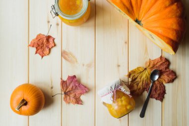 Sonbahar natürmort organik kabak, kabak reçeli bir kavanoz, akçaağaç yaprakları ve kaşık üstten görünüm doğal ahşap masa, stok fotoğraf görüntü üzerinde