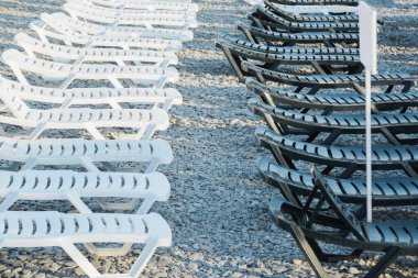 sahilde arka arkaya plastik beyaz ve siyah şezlong