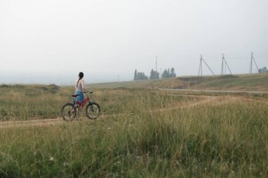 beyaz beyaz genç kadın köy yolunda döngüsü ile gidiyor