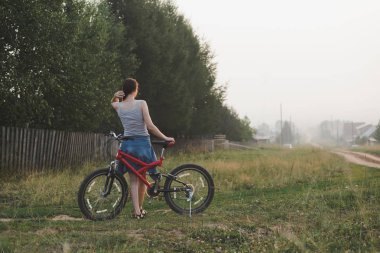 köyde bahçe yakınında bisiklet kırsal ile ayakta genç kadın