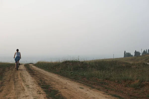 Взрослая женщина на велосипеде по сельской дороге — стоковое фото