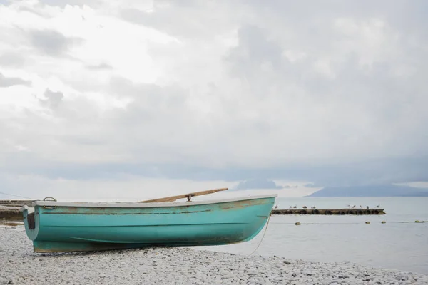 small wooden fishing azure boat on pebble coast black sea beach