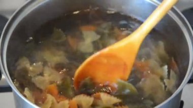 ahşap kaşık ile avrupa kadın metal kase kaynar suda renkli yay makarna farfalle karıştırır, full hd stok video görüntüleri üst görünümü kadar yakın