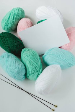 Akrilik yumuşak pastel renkli yün iplik yumağı ve beyaz arka planda iğneler, üst görünüm düz dikey stok resim maketi ile metin için metin alanı ile birlikte yatar