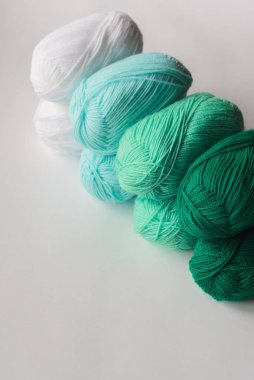 akrilik yumuşak pastel yeşil, gök mavisi ve beyaz renkli yün iplik şeritleri beyaz arkaplan üzerinde satır, üst açı görünümü, metin için metin alanı ile dikey stok fotoğraf