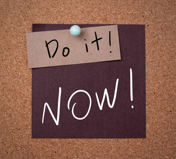Черная наклейка с надписью "Сделай это сейчас!" текст, нанесенный на пробковую доску