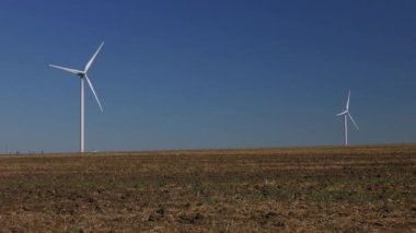 Mavi gökyüzüne karşı iki rüzgar türbini.