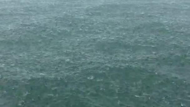 Ulewny deszcz spadnie na powierzchni morza. — Wideo stockowe
