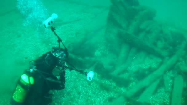 Onderwater Archeologie: een fotograaf fotografeert de overblijfselen van een houten zeilschip. — Stockvideo