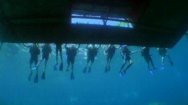 Dalış eğitimi: yüzen platformun kenarında bir grup öğrenci dalgıç, alt görünüm.