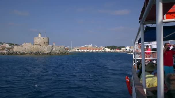 古塔和港口入口在一艘移动的游艇的船尾后面.希腊罗得岛. — 图库视频影像
